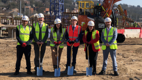 Rachel Hopkins, Labour MP for Luton South and South Bedfordshire, stands for a photo with other local dignitaries on the site of The Stage flagship regeneration scheme. They are wearing hard hats and fluorescent jackets with construction work happening in the background.
