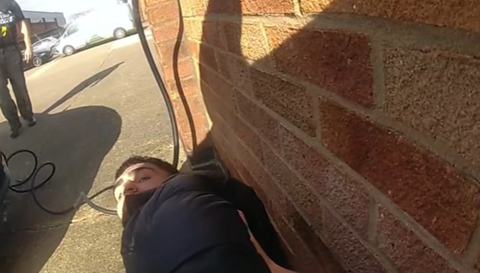 Ibrahim Hamad looking back from living on the floor with a brick wall to his left.