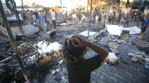 A child inspects the charred remains of a an area hit by an Israeli strike in Gaza