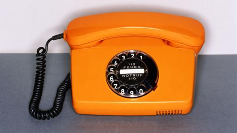 Image of an orange rotary dial telephone