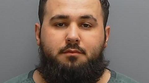 A custody shot of Rrahim Statovci, a man with short hair and a large beard.