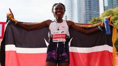 Ruth Chepngetich holds up a Kenyan flag after winning the Chicago Marathon 