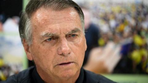 A close-up image of former Brazilian President Jair Bolsonaro shows him in a black top looking ahead