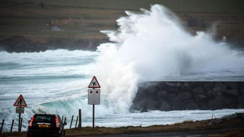 Large waves are seen colliding with land in a quiet coastal town the Shetland 