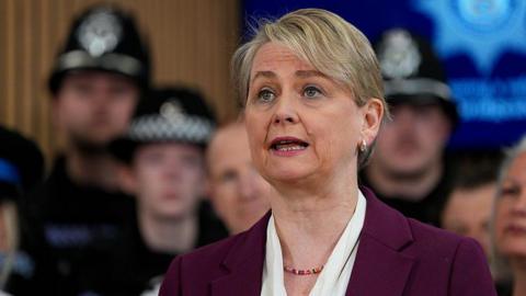 Yvette Cooper speaks. She is wearing a maroon suit. 