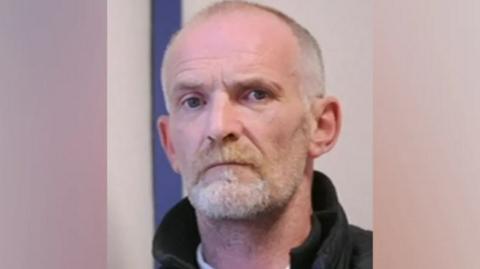 Man with shaved head and goatee beard wearing coat