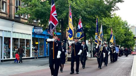 Military standard bearers march down Leicester High Street