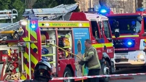 A firefighter pulling a high-pressure water hose from a fire engine on a street