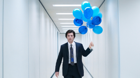 Adam Scott as Severance's Mark Scout holding blue balloons in a sanitised white office hall