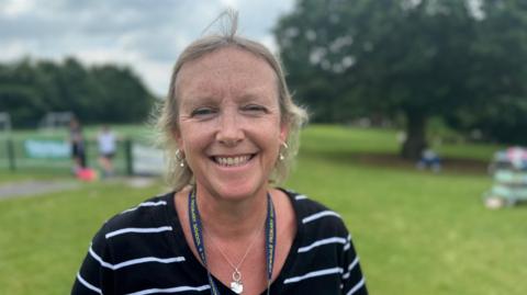 Headteacher Rachel Cook is wearing blue and white striped top and is smiling into the camera.