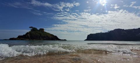 Mainly blue sky above the sea with headland in the distance