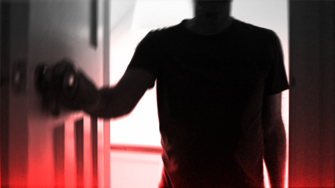 A dark silhouette of a person wearing a short-sleeved shirt is positioned in the foreground, facing a door. The person is using their left hand to grasp and turn a doorknob. The background is brightly illuminated, casting the figure into deep shadow and creating a high-contrast effect. A red gradient overlays the bottom portion of the image, contributing to an eerie or dramatic atmosphere