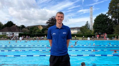 Man standing in front of outdoor swimming pool