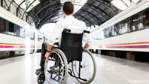 Man waits for train in wheelchair