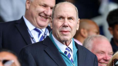 Michael Eisner stands in the crowd at Portsmouth, in shirt and tie, watching on intently