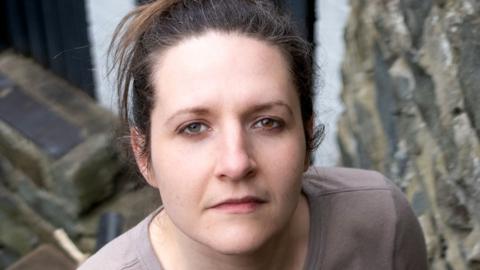Ruth has dark hair and is looking directly at the camera.
