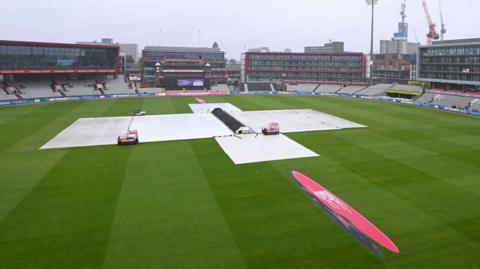 Old Trafford with covers on as rain falls