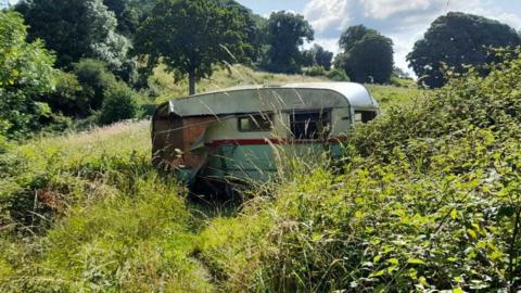 Old caravan in a green field