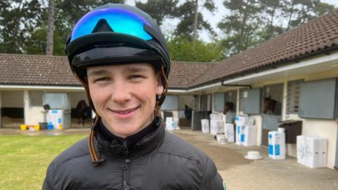 Jockey Billy Loughnane standing in his racing hat with visor at the Craven House Stables in Newmarket.