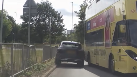 A Nissan Qashqai approaching a yellow bus head-on.