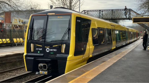 A Merseyrail train arrives at a station