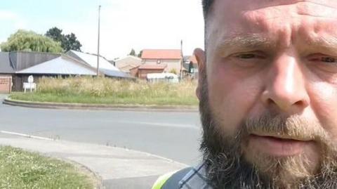 A man's head in a selfie-shot video at the roundabout