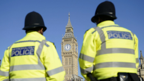 Part of the Palace of Westminster is seen between two Metropolitan Police officers in Parliament Square, London. 
