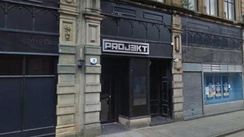 A black-front building with 'projekt' written in silver font above the door.