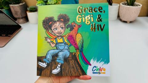 The front cover of a book titled 'Grace, Gigi & HIV'. There is an illustration of a child with curly hair in bunches sat on a tree stump while interacting with a colourful parrot. There is branding in the bottom right hand corner that says 'Chiva' in colourful lettering.