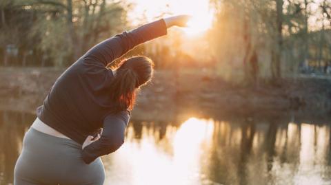 The back of a person stretching outside.