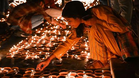 People light earthen lamps on the banks of Sarayu river during a programme, on the eve of Diwali, on November 11, 2023, Ayodhya