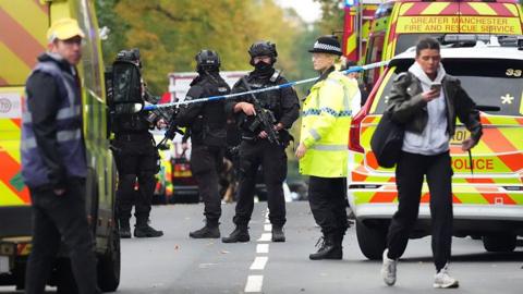 Armed Police, emergency responders and congregants gather near the Heaton Park Hebrew Congregation Synagogue 