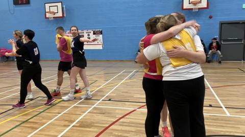 A group of netball player hugging 