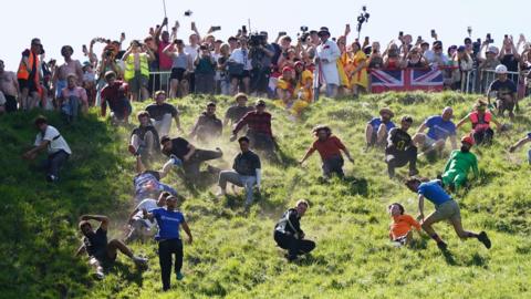 Dozens of competitors tumble downhill at the Gloucestershire cheese rolling event