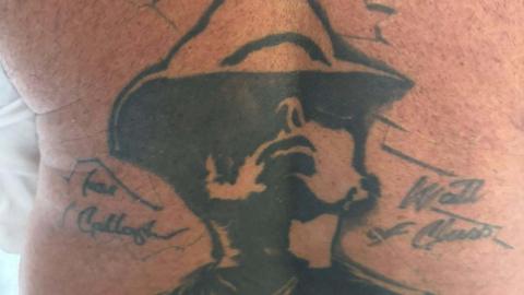 A large tattoo on a man's back on Liam Gallagher wearing a hat