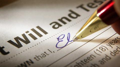 A close up of a pen filling in a will document