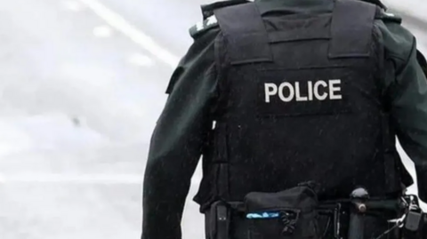 A police officer wearing a bulletproof vest with 'police' written on the back.