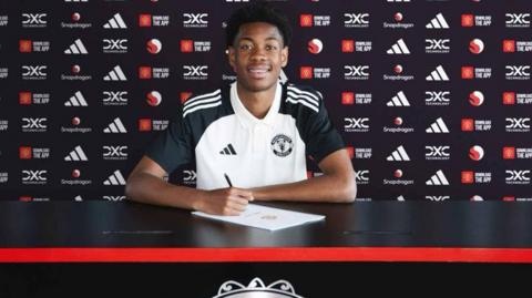 Enzo Kana-Biyik signing his Manchester United contract