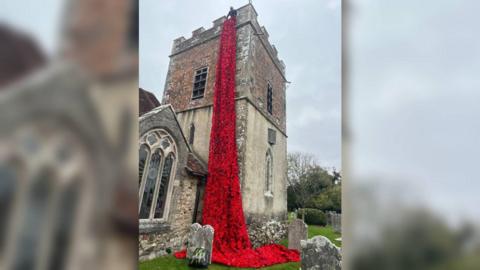 A waterfall of knitted poppies coming down the side of Boldre church in the New Forest.