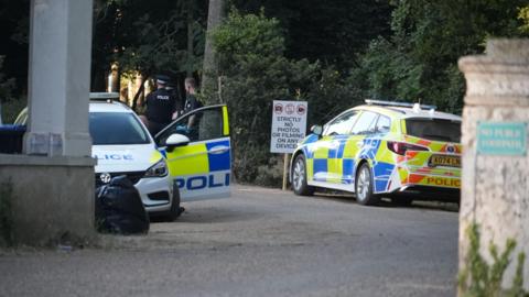 Two police cars parked at Shrubland Hall.