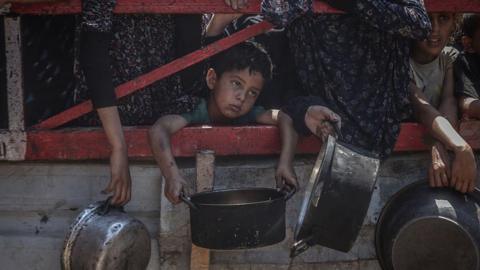 Crowds form as Palestinians, including children, line up in Gaza City, Gaza to receive food distributed by a charity.