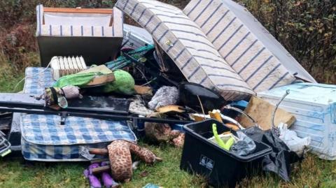 A pile of waste fly-tipped at Conce Moor in Cornwall. It includes a sofa, mattress, fridge, electric radiator and metal clothes airer. 