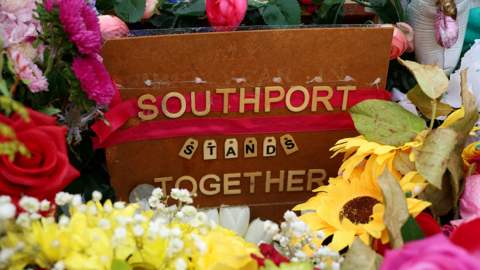 Flowers left in memory of the victims of the Southport attacks of 29 July 2024. Among the flowers is a placard that says 'Southport stands together'