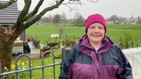 Woman stood in front of fenced garden