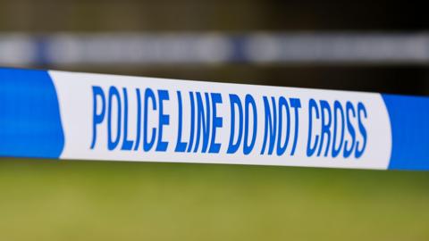 Blue and white police tape bearing the words: "Police line do not cross"