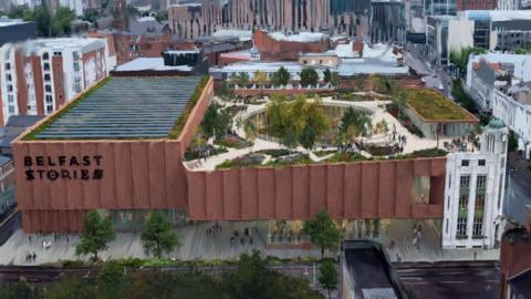 A computer-generated image of Belfast Stories. It shows an aerial view of the Belfast skyline, with a focus on a large, brown building with a garden on its roof.