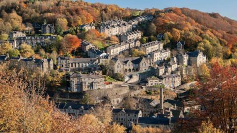 A picture of houses built in a valley surrounded by trees