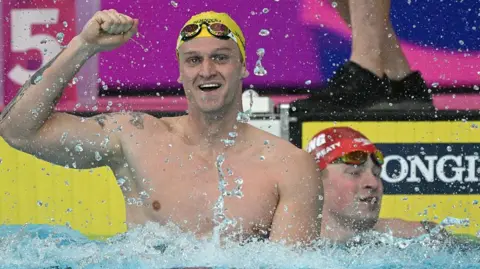 Sam Williamson celebrates winning, with Adam Ramsay-Peaty in the background