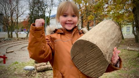 A young child holding a log