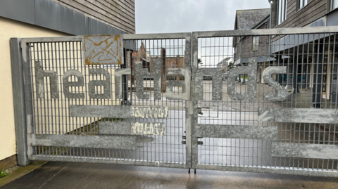 A picture of the entrance to Heartlands. It is a silver gate which is the entrance.